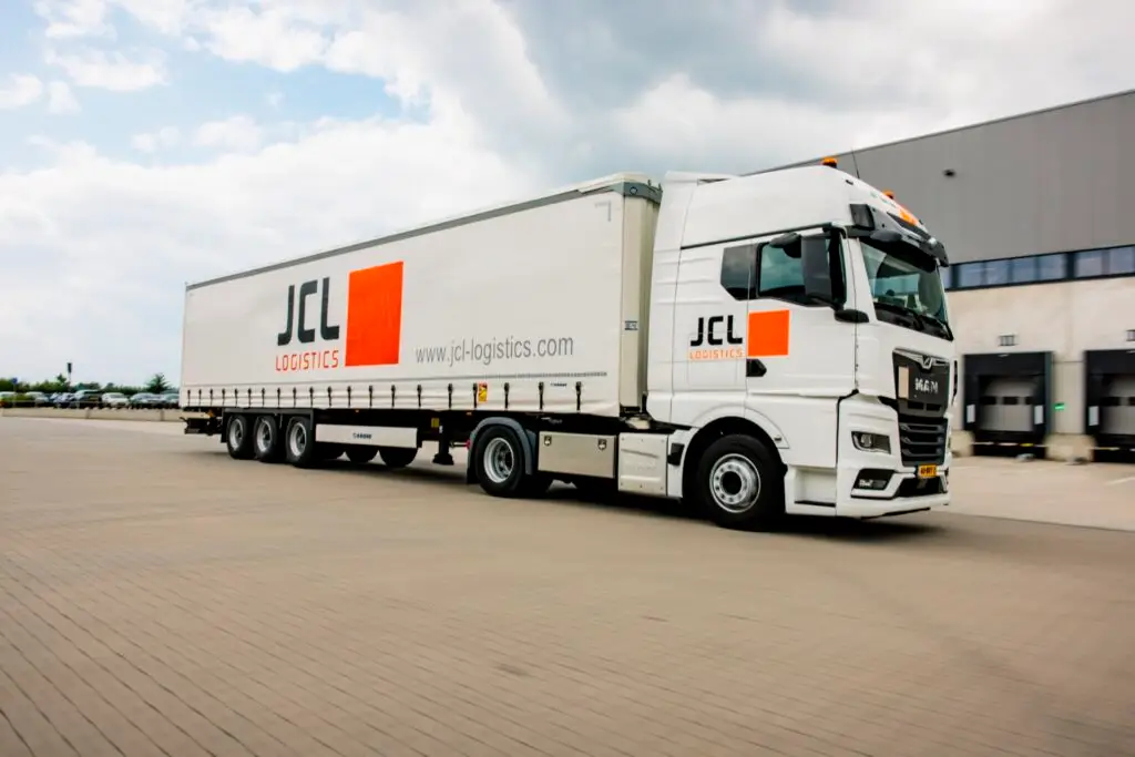 JCL Logistics vrachtwagen met trailer onderweg bij het distributiecentrum